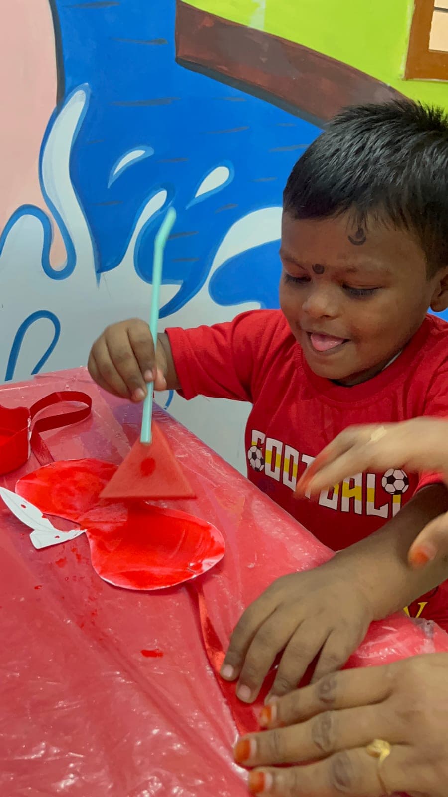 Giggling preschooler exploring red craft materials during Red Day colour-learning activities